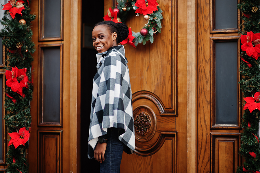 woman in checkered cape opens wreath decorated door to a consistent and iconic brand identity