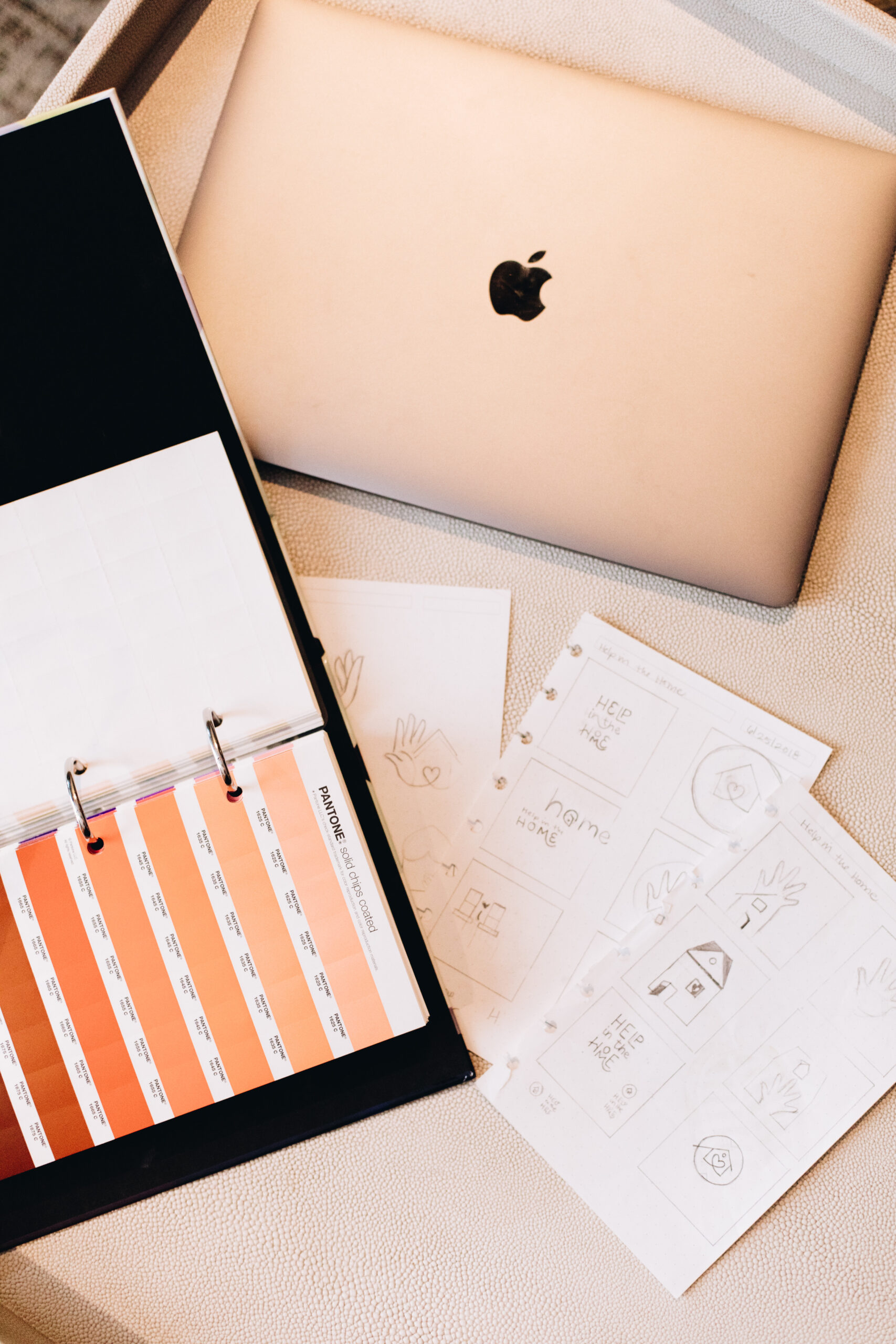 MacBook Pro with Pantone chips and brand sketches in rose gold hues — visual identity design process for branding women leaders.